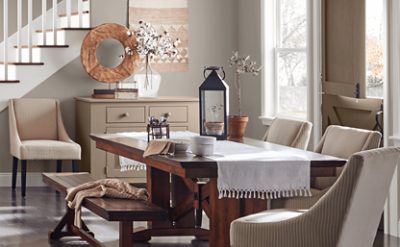 A farmhouse dining room with large family table, bench seating and gray walls